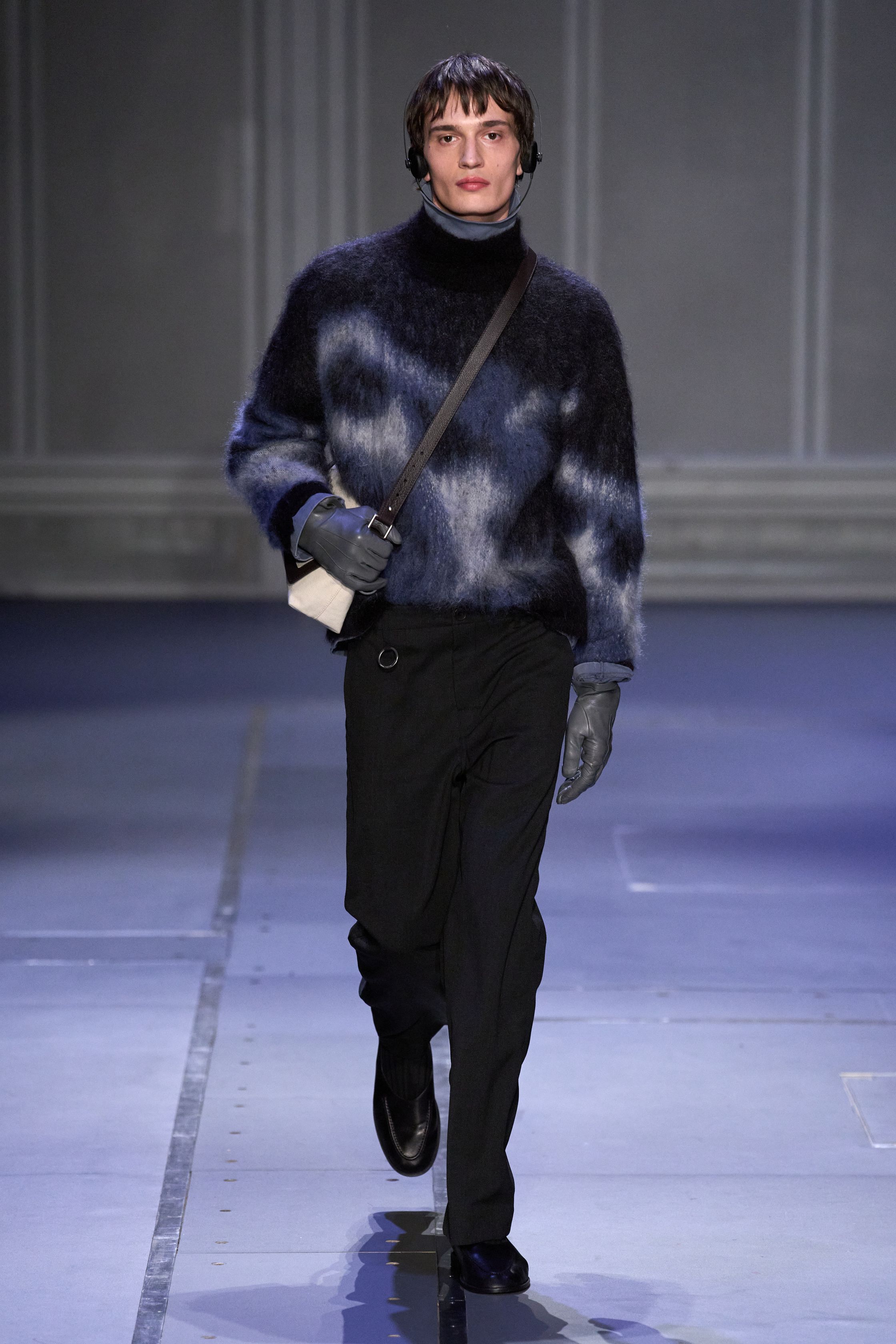 Études Studio 26FW 延续其标志性的“巴黎青年智识气质”，在克制的灰、棕、墨绿与深紫中，将街头轮廓与艺术语境并置。摄影肖像印花、皮革长风衣、渐变针织与蓬松羽绒共同构建出一种略带疏离感的城市诗意。系列并不追求强烈戏剧冲突，而是通过材质反差与比例控制，呈现介于学院派、亚文化与当代艺术之间的中间地带，体现 Études 一贯的文化策展式设计方法美-顽石频道趋势研究